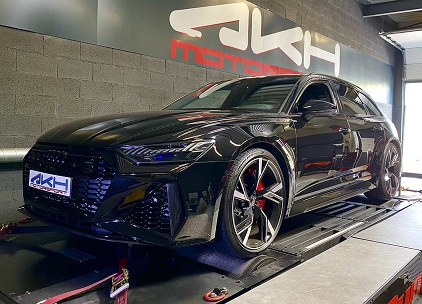 Audi RS6 noire sur un banc de puissance, avec le logo AKH Motorsport visible sur le pare-chocs et sur le mur en arrière-plan.