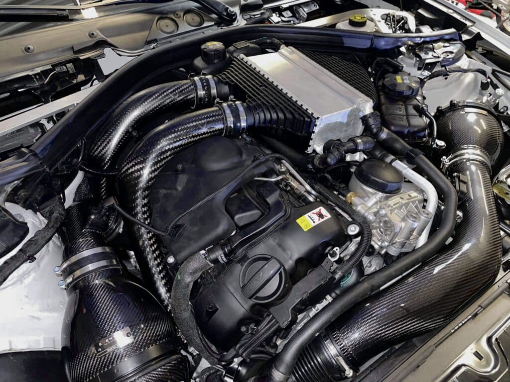 Moteur de voiture détaillé avec un système d'admission Eventuri en fibre de carbone, intercooler et nombreux composants.